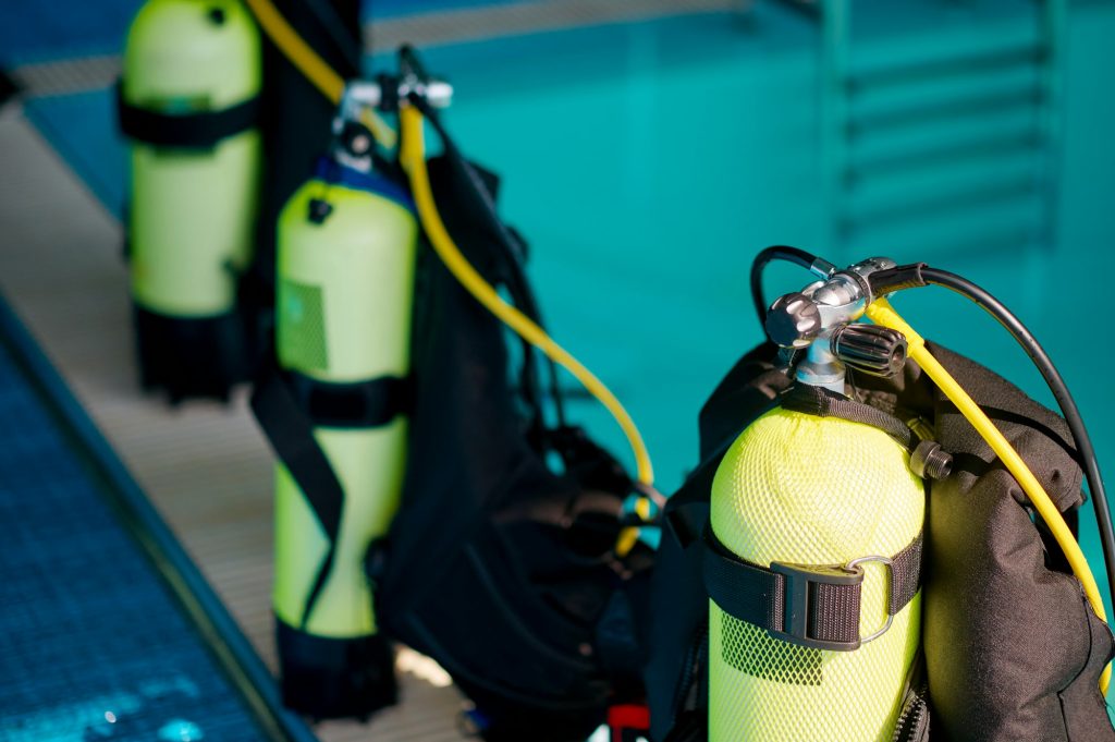 Three oxygen tanks at poolside, diving equipment